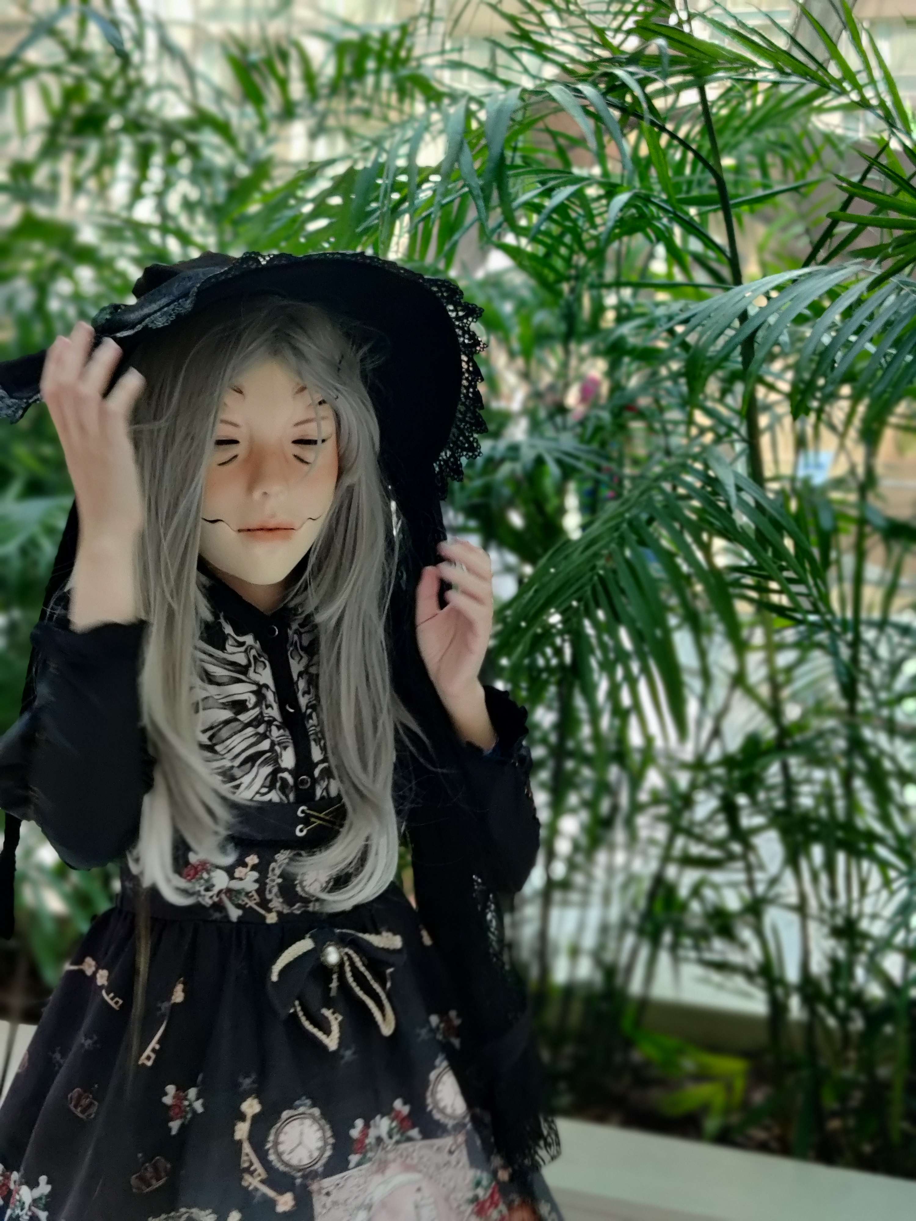 Person in a doll mask in gothic lolita, with a witch hat