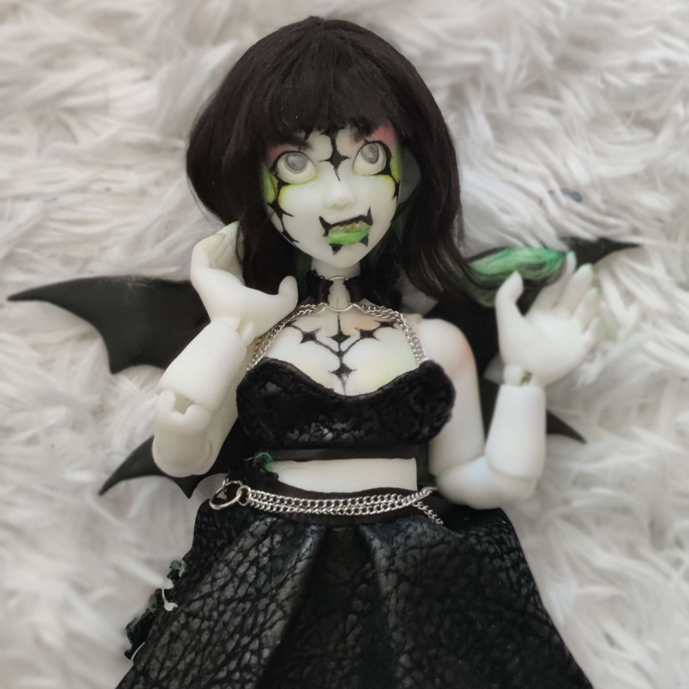A doll wearing black leather with black bat wings